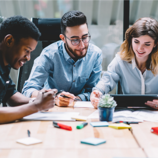 Three individuals sitting at a table in a collaborative work enviroment - Nexusmind